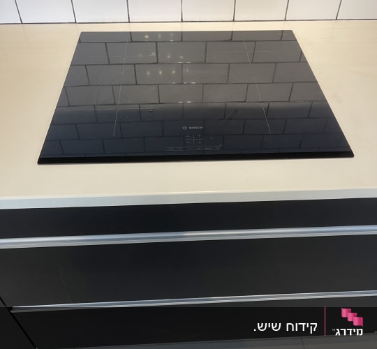 משטח שיש בהיר במטבח מודרני עם כיריים אינדוקציה מותקנות
